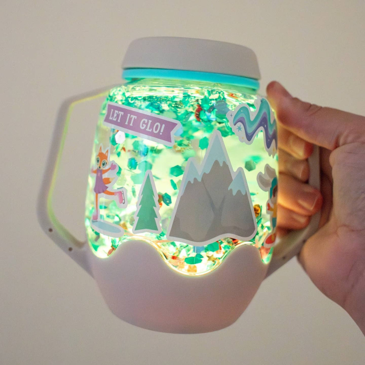 Hand holding a glowing jar with mountain and animal designs, labeled 'Let It Glo!'.
