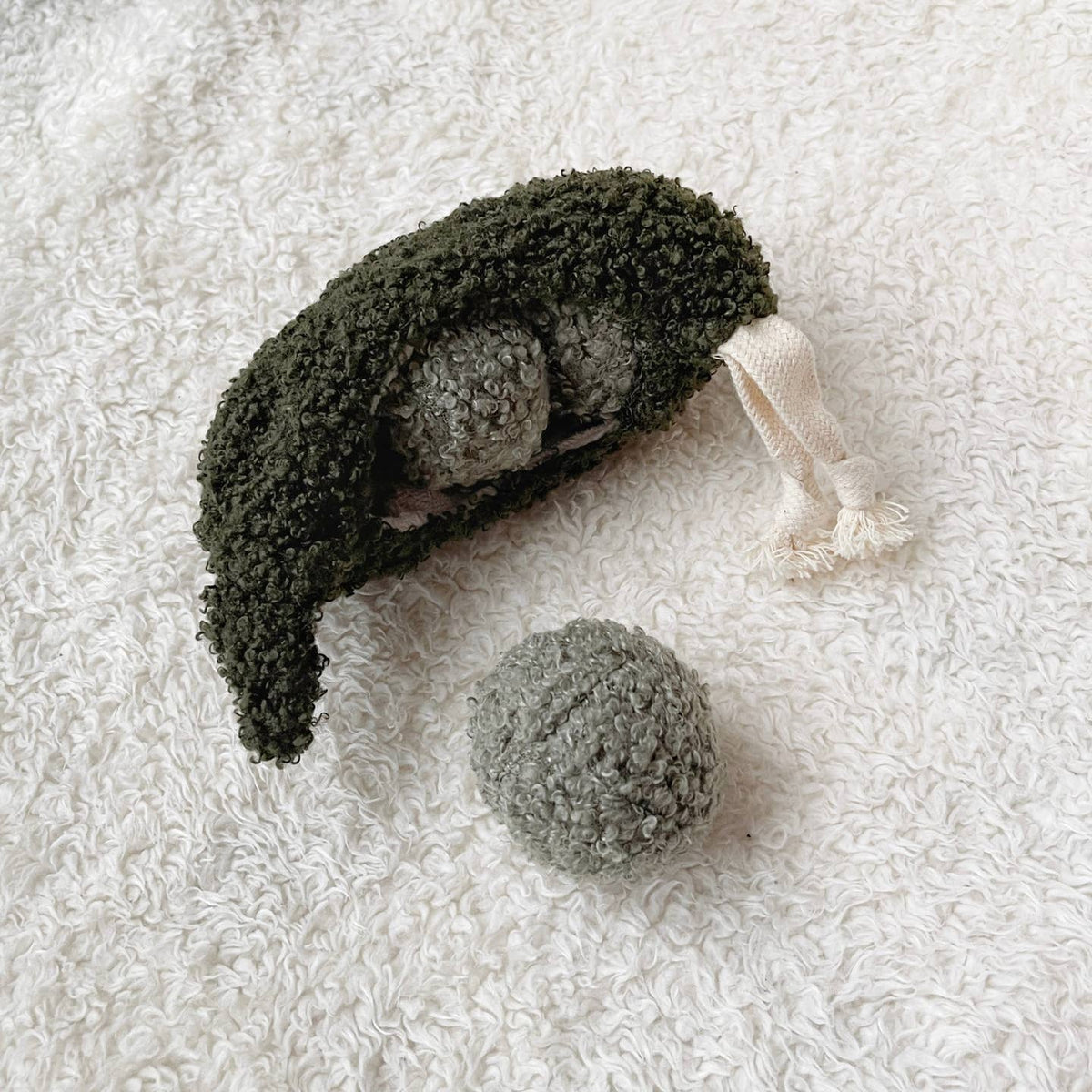 Textured green and gray plush toy on a white textured surface