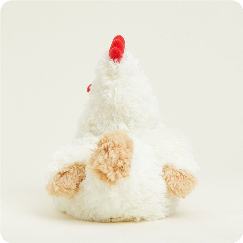 A fluffy white Warmies chicken plush toy viewed from behind, showing its brown tail feathers, wings, and bright red comb against a plain background.