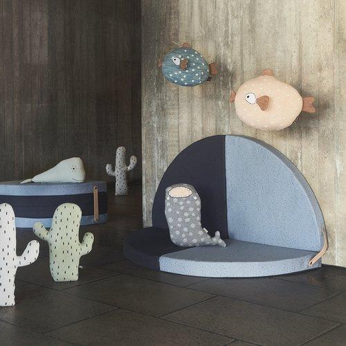 Children's room with plush toys shaped like fish and cacti on a wooden floor.