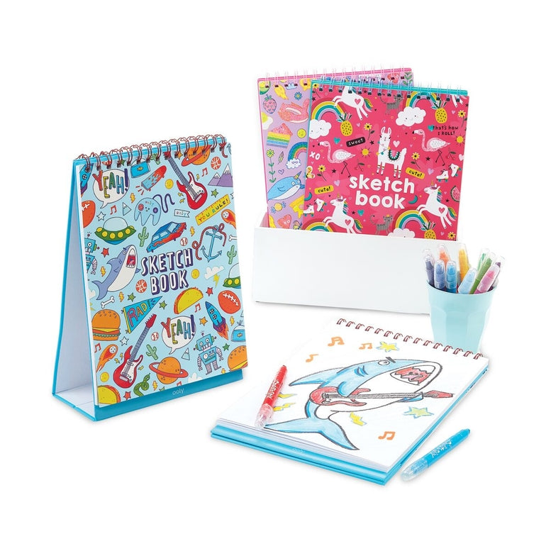 Colorful sketch books with a shark drawing and stationery items on a white background