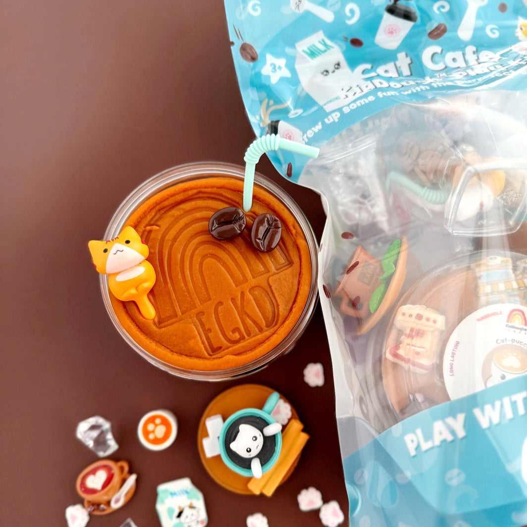 Cup of coffee with a bear-shaped stirrer, surrounded by small decorative items on a brown surface.