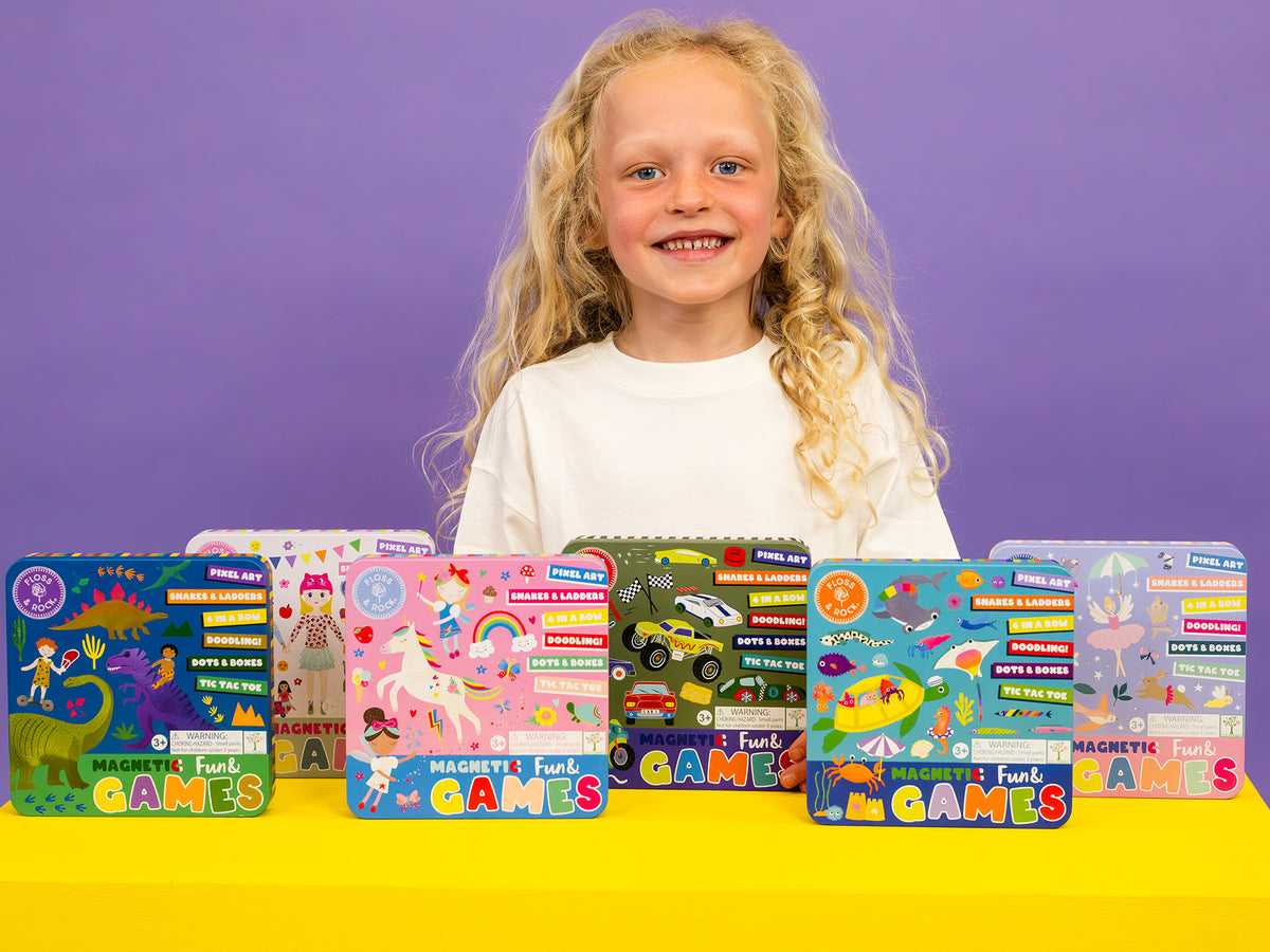 Young girl with a row of colorful game boxes on a yellow table against a purple background