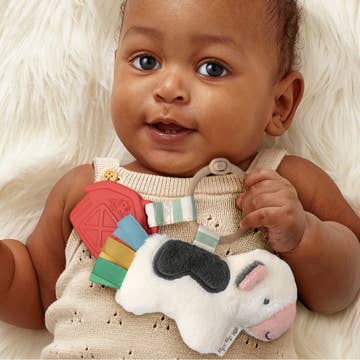 Baby holding a colorful toy with a white fluffy background