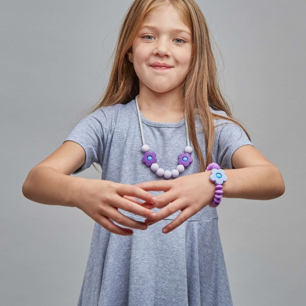 Young girl wearing a light blue dress with a necklace on a gray background