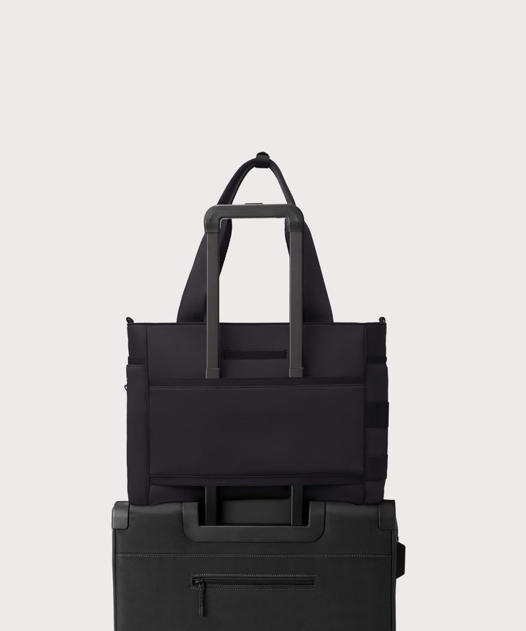 Black tote bag with multiple compartments on a light gray background