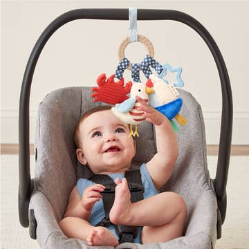 Baby in a car seat with colorful hanging toys