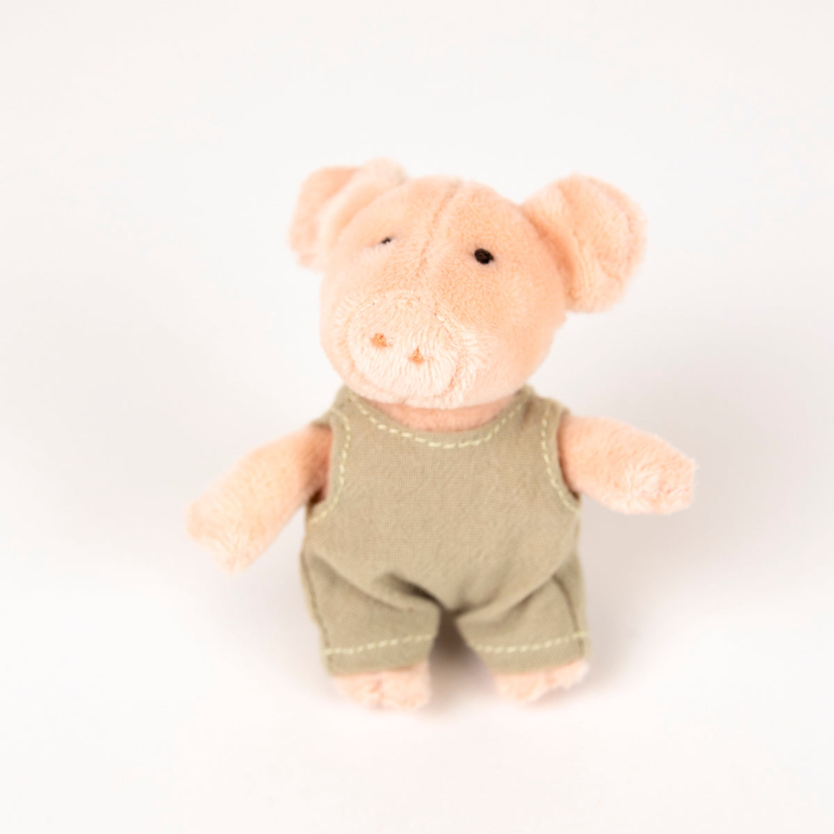 plush pink pig with beige romper - view from the front on a white background
