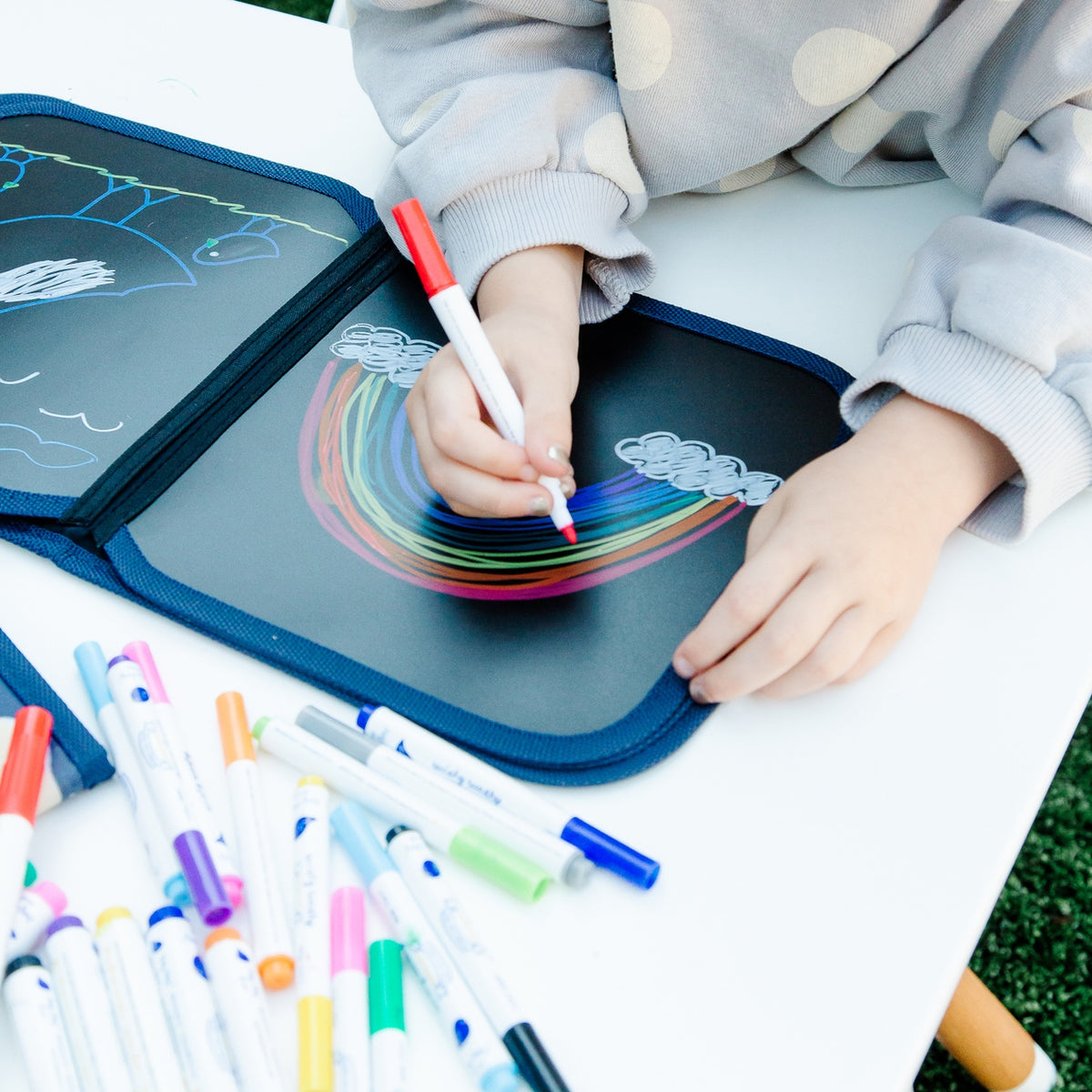 Child drawing on a portable chalkboard with colorful markers.