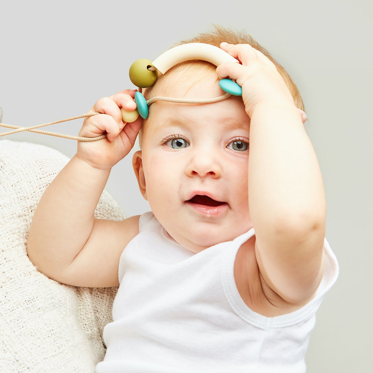 Baby playing with a toy on a plain background