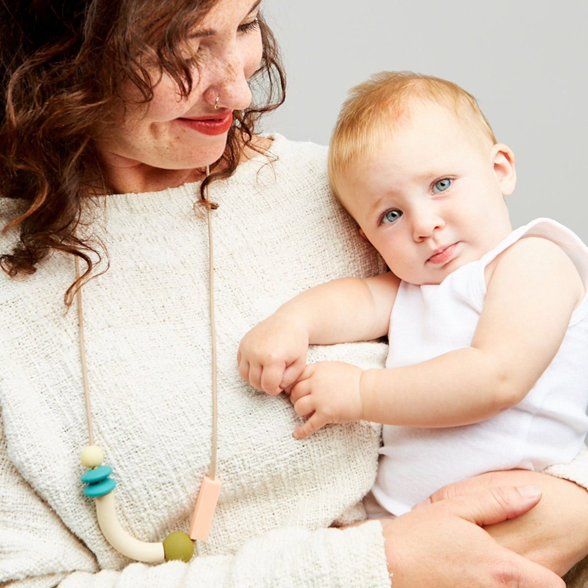 Woman holding a baby against a plain background