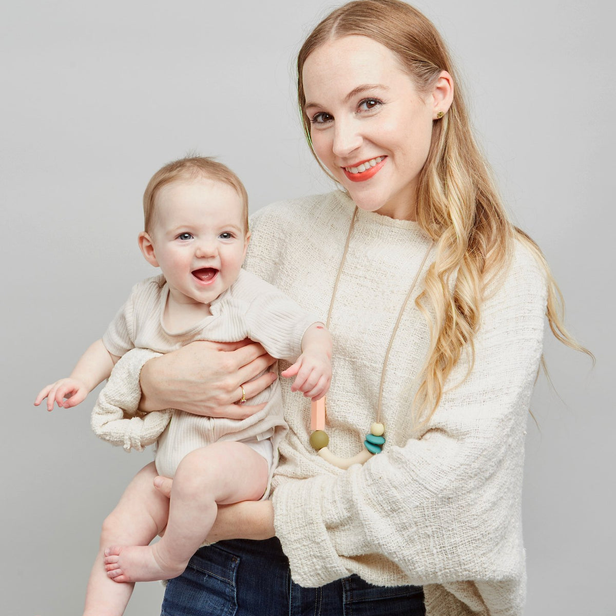 Woman holding a baby against a plain background