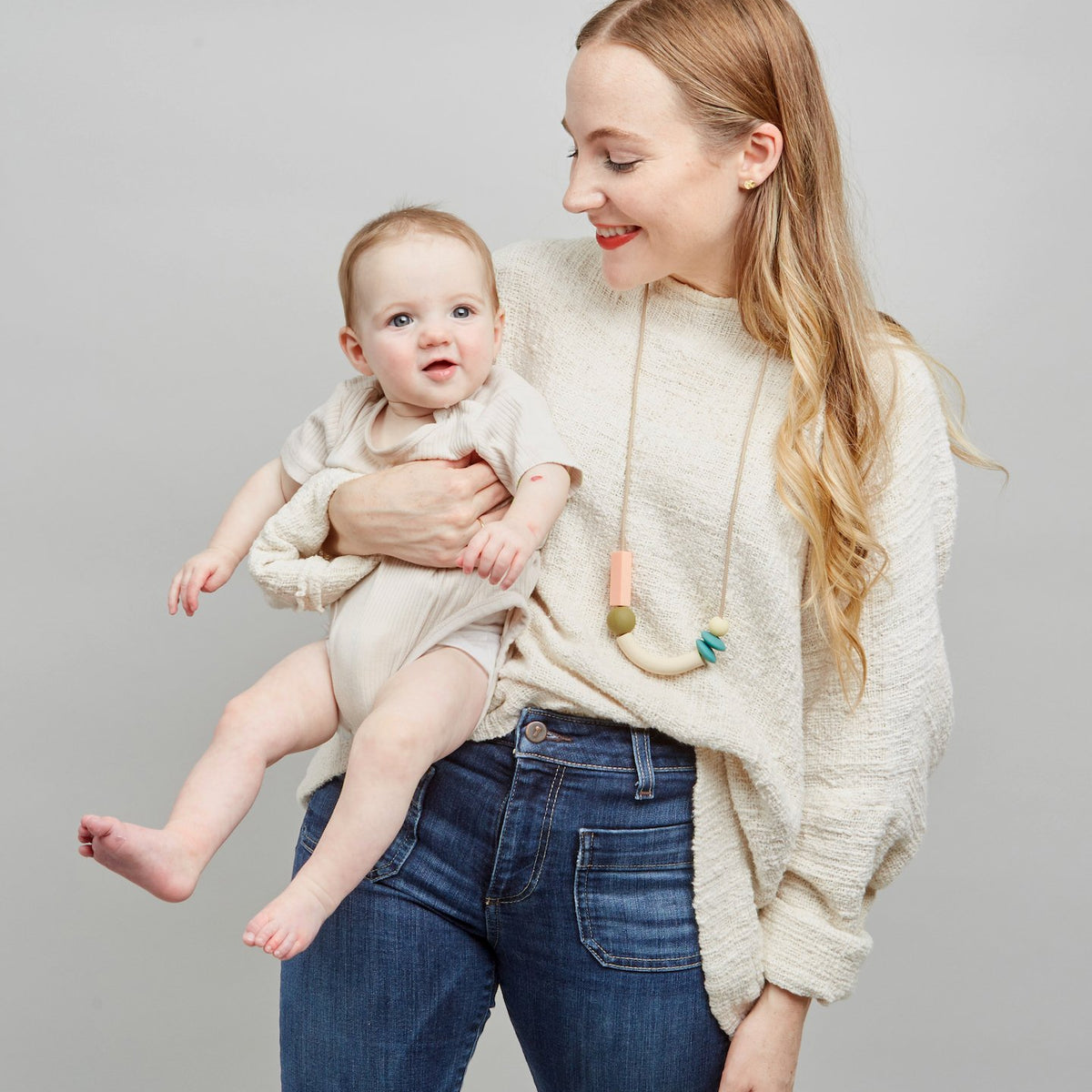 Woman holding a baby against a plain background