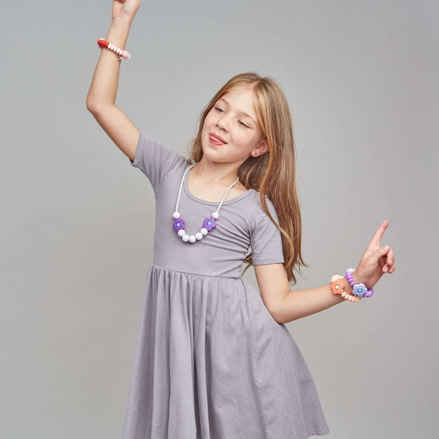 Young girl in a gray dress with jewelry on a gray background