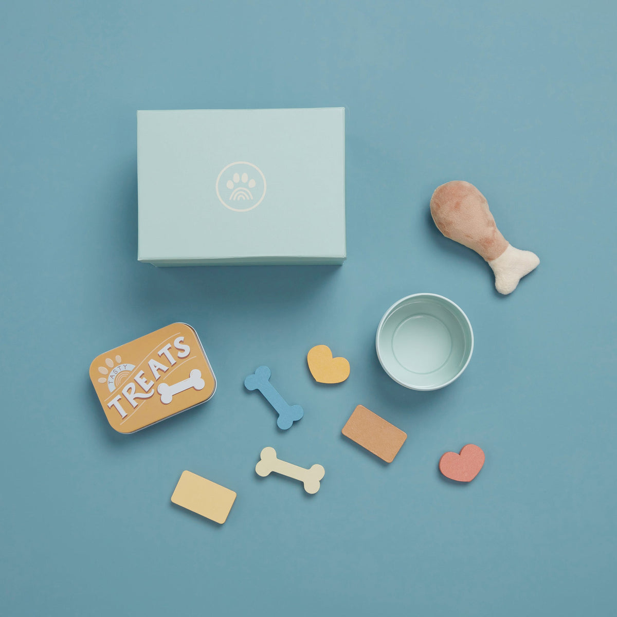 Dog-themed items including a box, bowl, and various dog toys on a blue background