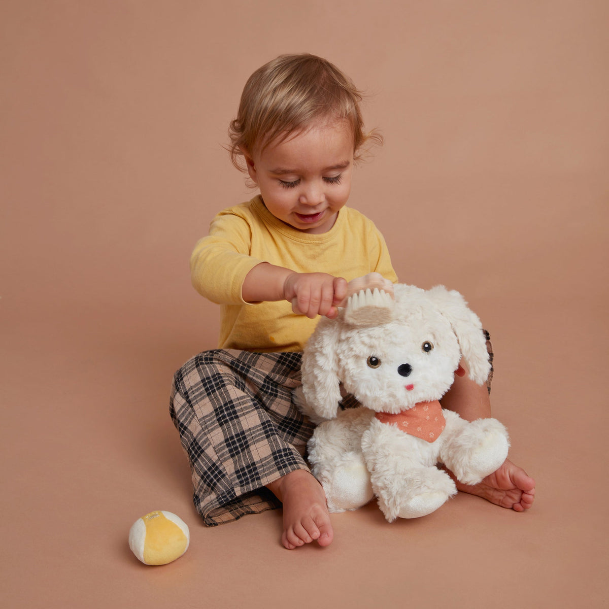 Child playing with a white teddy bear on a brown background