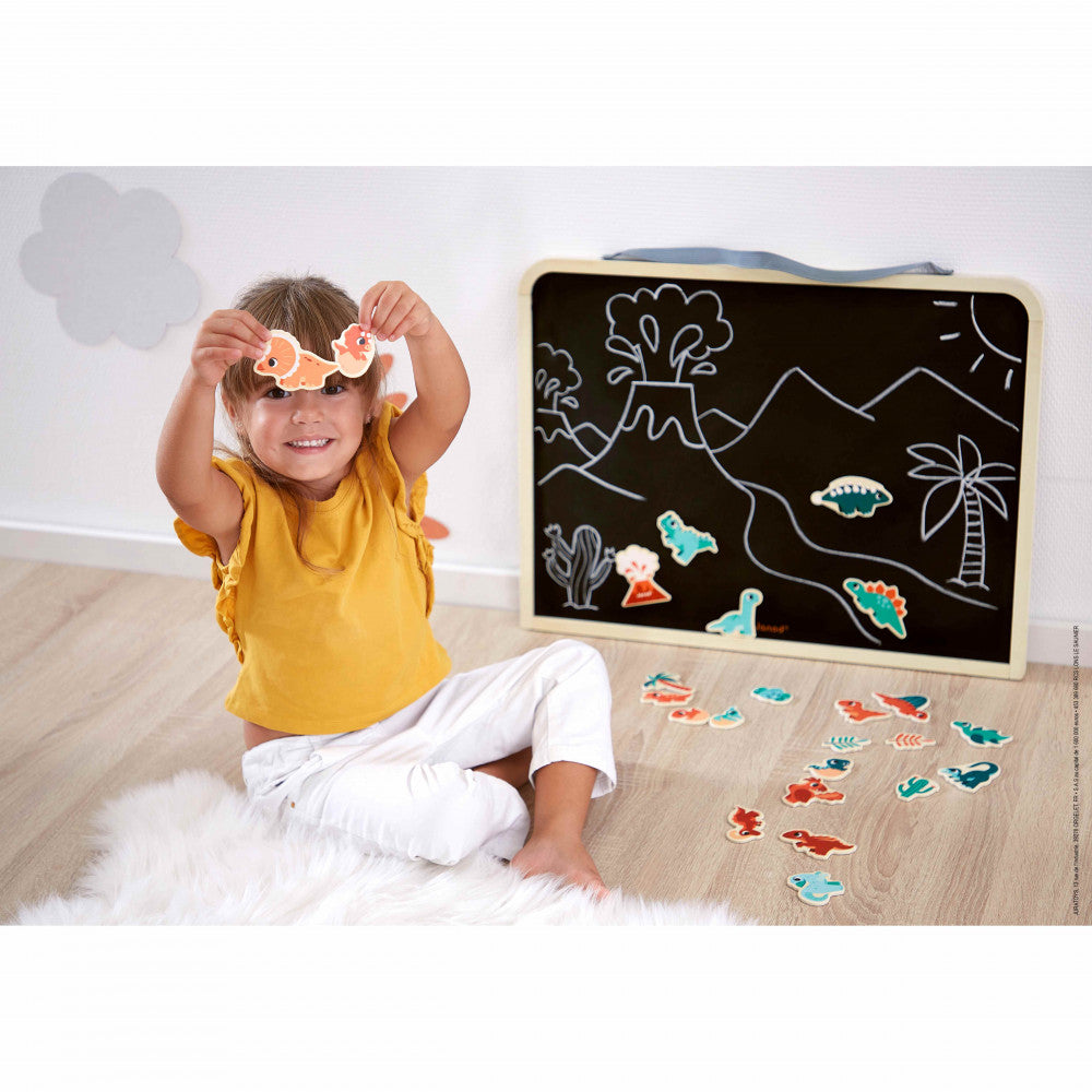 Child playing with stickers and a blackboard with drawings on a wooden floor.