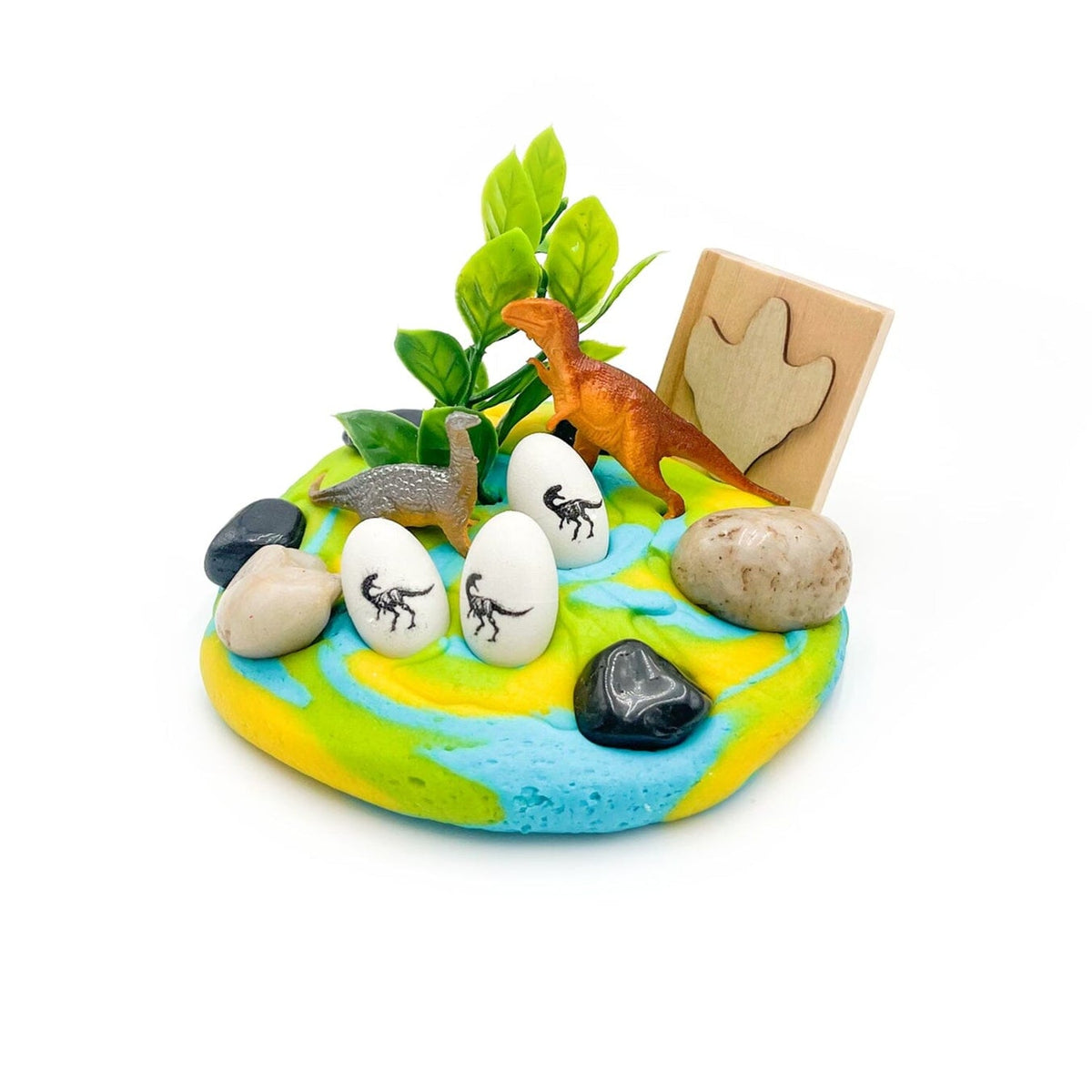 Miniature diorama with dinosaur figures, eggs, and plants on a white background