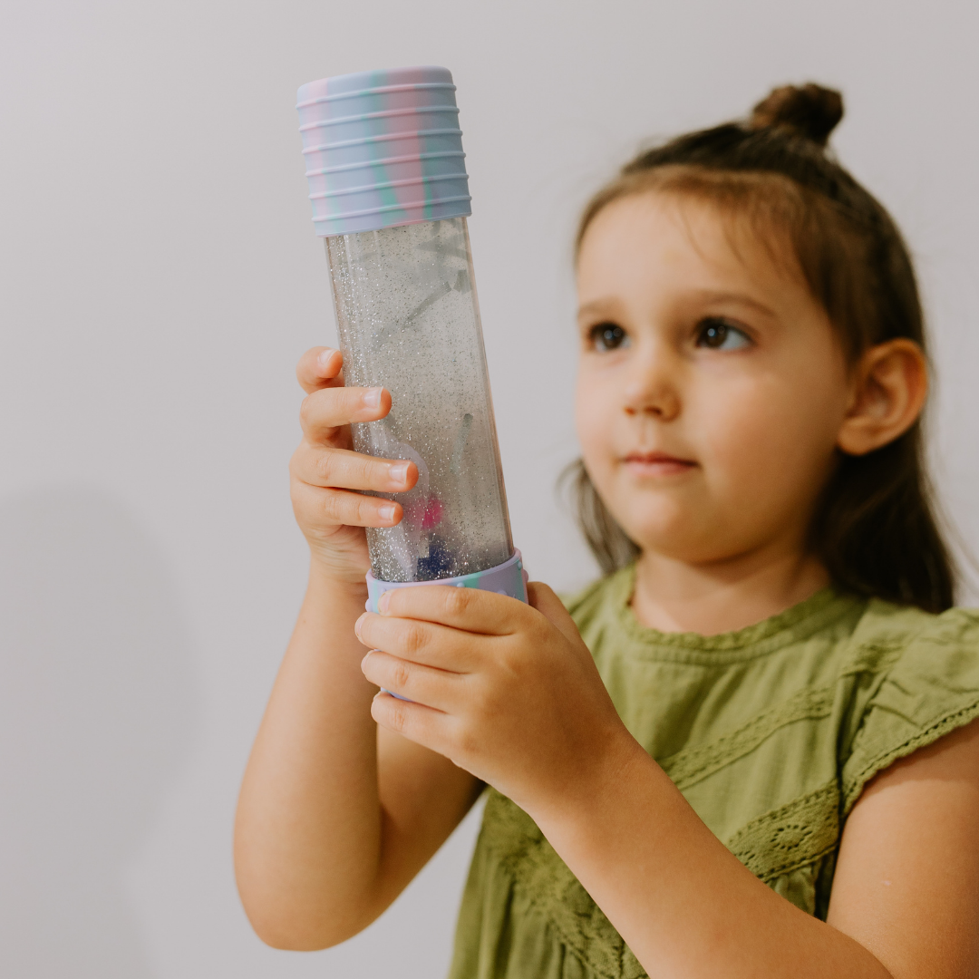 Young girl holding a colorful tube toy against a plain background