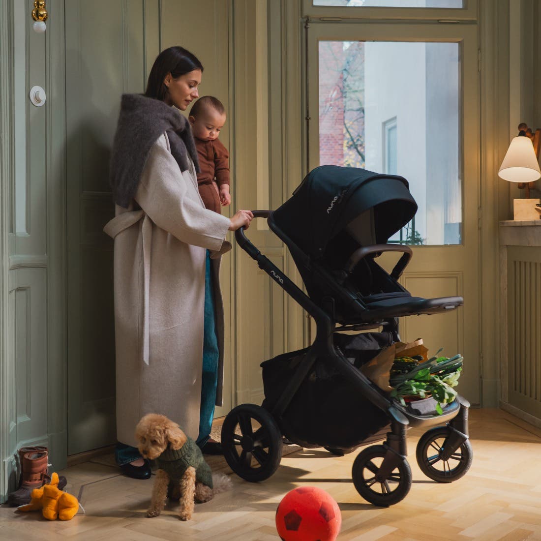Woman pushing a black stroller with a child in a room.