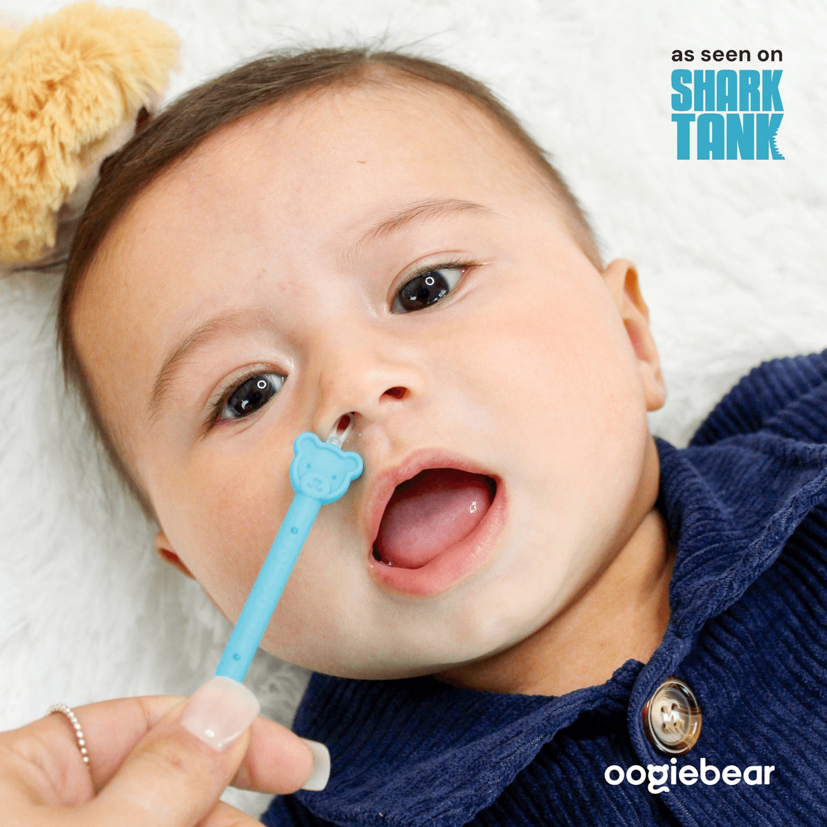 Baby with a blue toothbrush featuring a bear design, with 'Shark Tank' and 'oogiebear' branding.