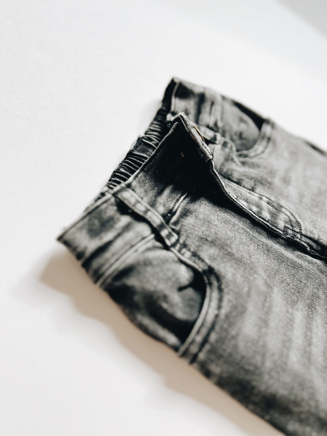 Close-up of a folded pair of black jeans on a white background
