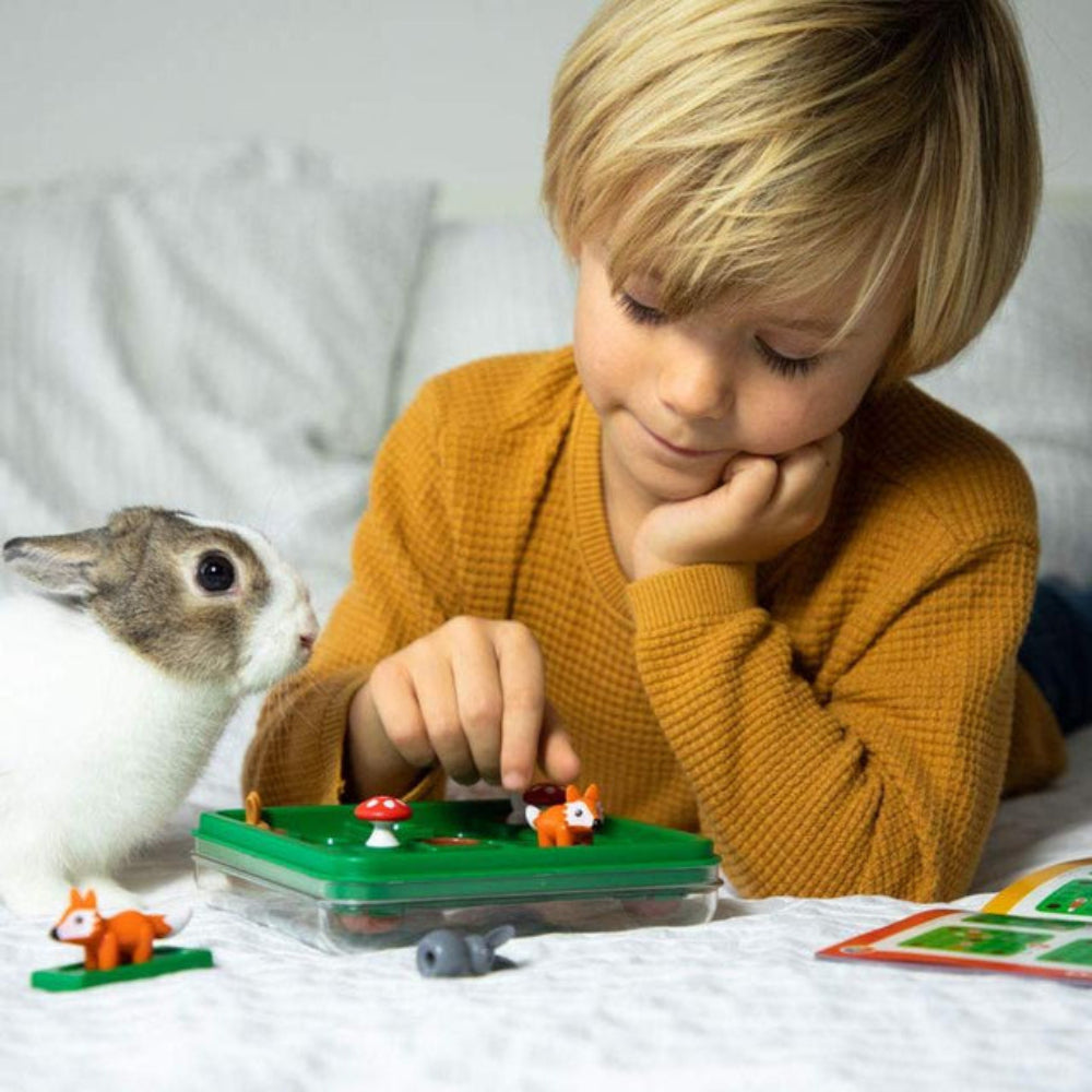 Child playing with a toy set on a bed next to a rabbit