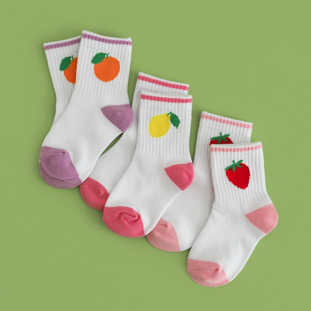 Set of four children's socks with fruit designs on a green background