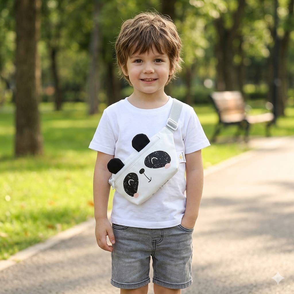 Child wearing a white t-shirt with a panda design and gray shorts, standing in a park.