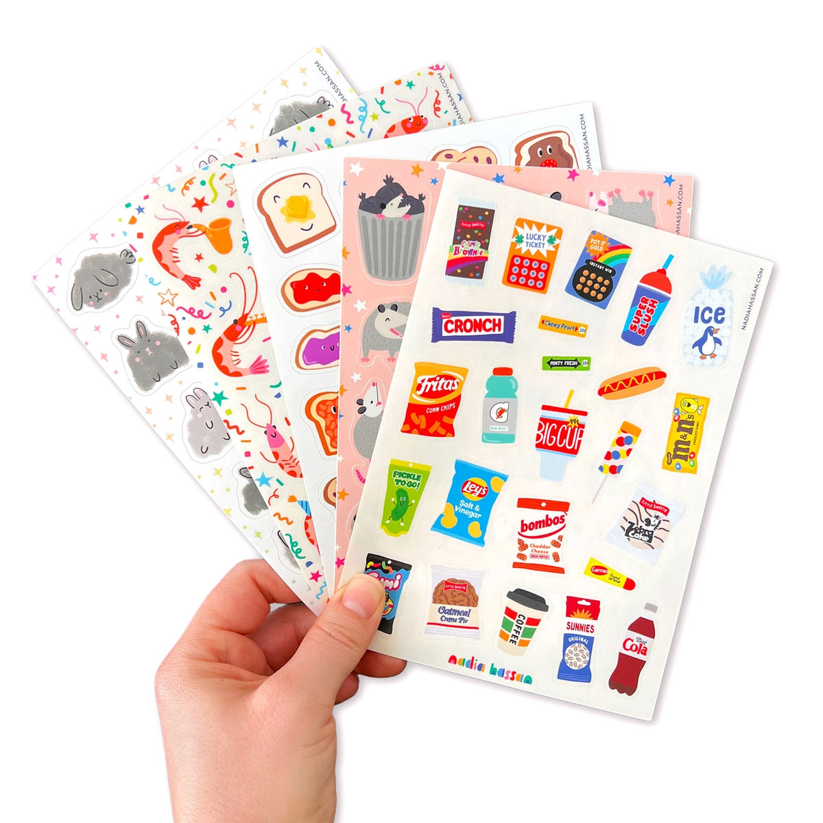 Hand holding a sheet of colorful stickers with various designs on a white background