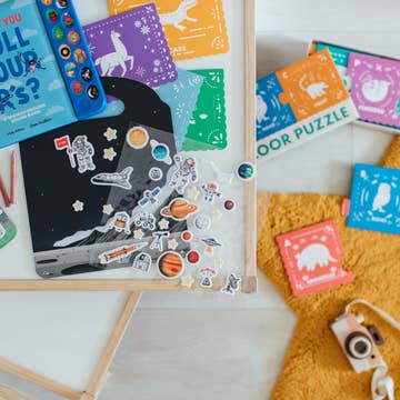 Children's educational toys including a space-themed puzzle and colorful books on a white surface.