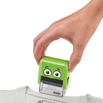 Hand using a green cartoonish stamp on a white shirt