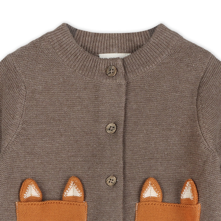 A close-up of a brown knit cardigan featuring two front pockets with fox-ear appliques in orange-brown and white, and brown buttons down the front.