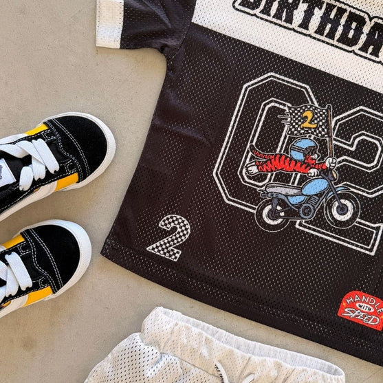 Children's birthday-themed jersey with matching shoes on a neutral background