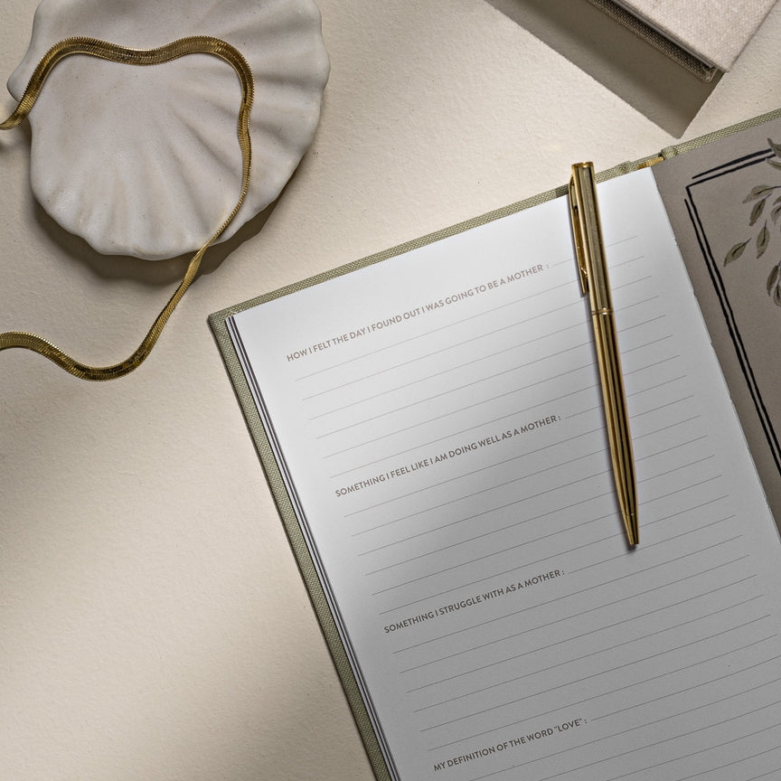Notebook with a gold pen on a beige surface, with 'Cafés' text in the background.
