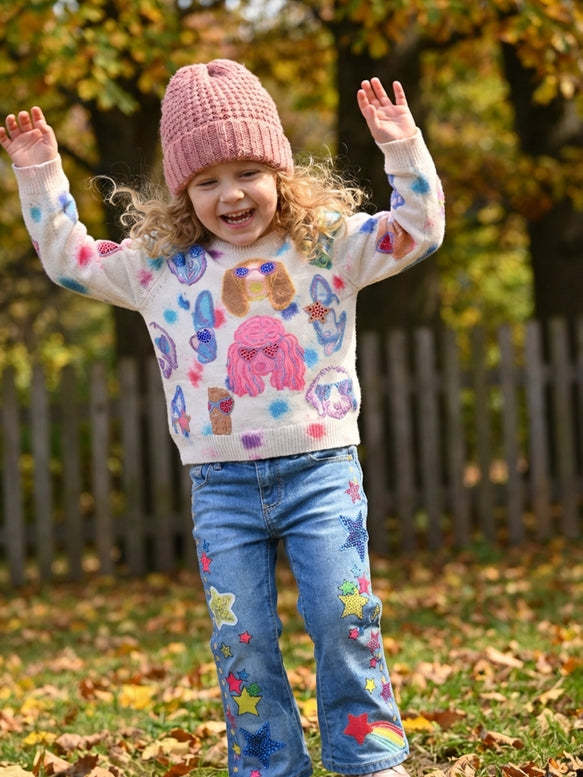 Child wearing a colorful sweater and jeans with patterns, standing outdoors in autumn.