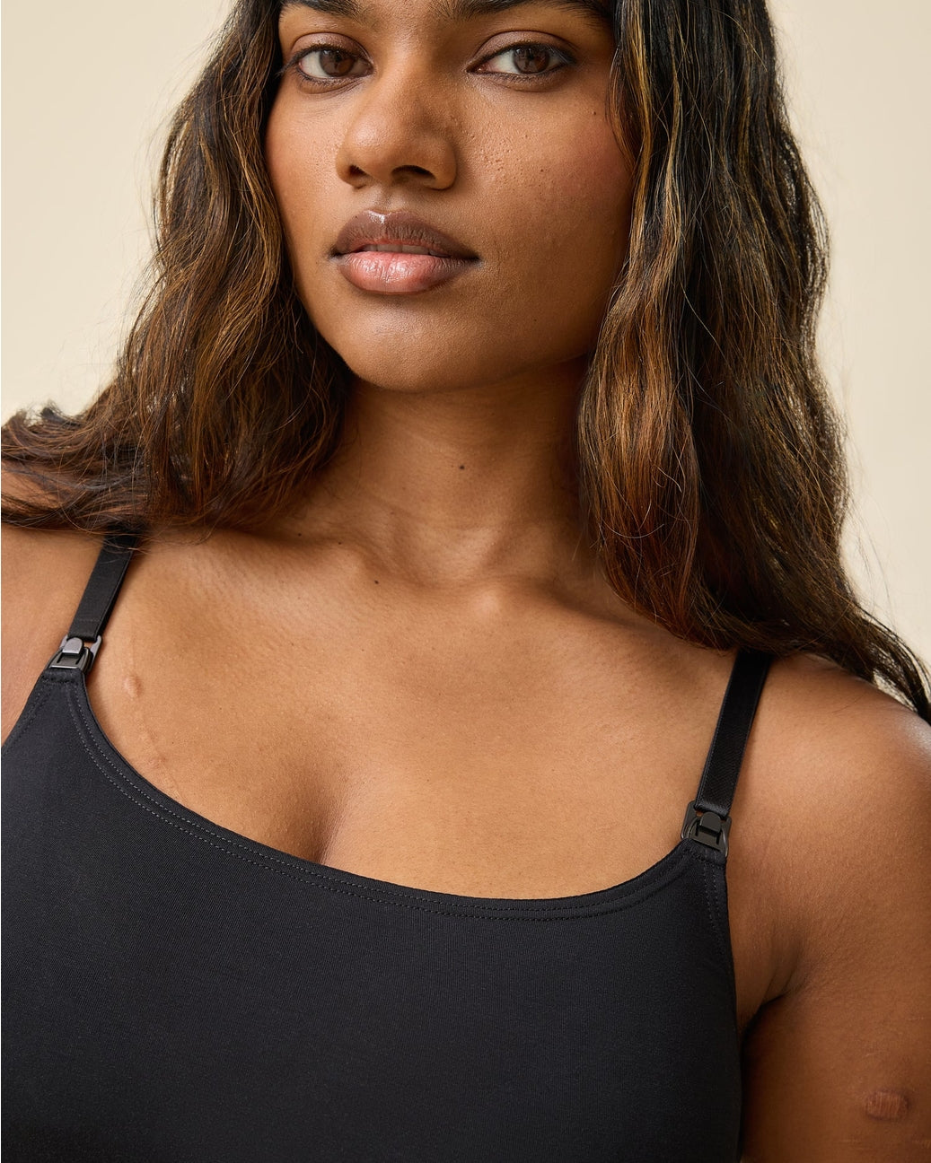 Woman wearing a black tank top against a neutral background