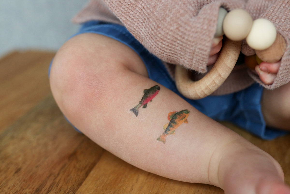 Child's leg with temporary fish tattoos on a wooden floor