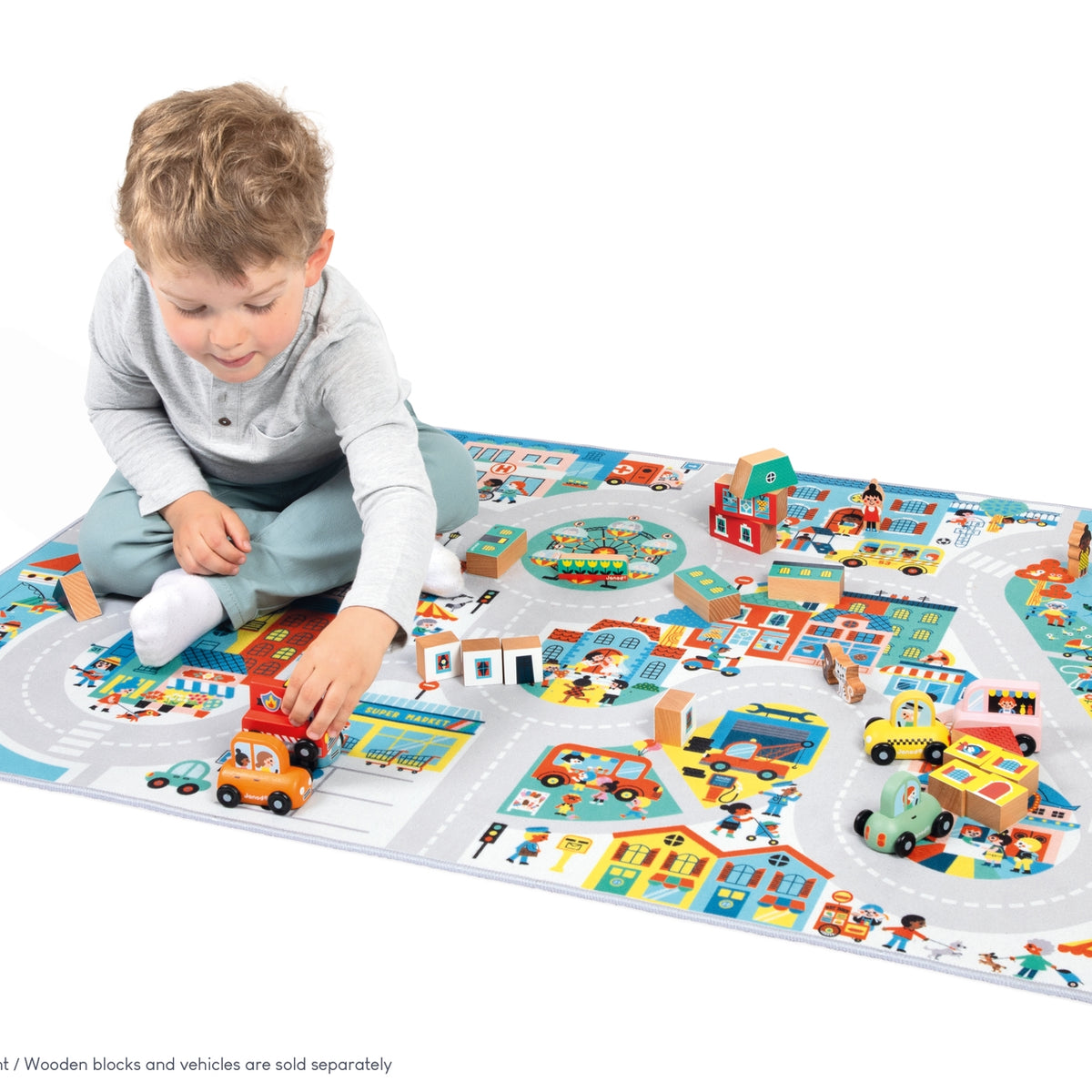 Child playing with a colorful toy mat featuring roads and buildings.