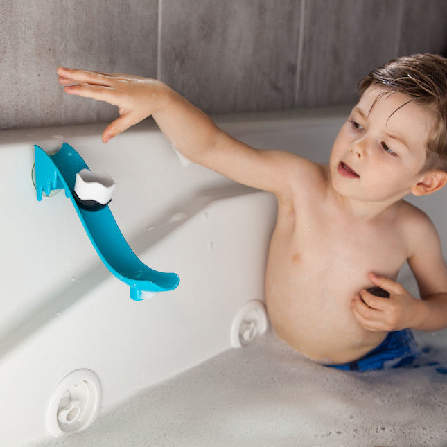 Child in a bathtub with a blue bath toy slide.