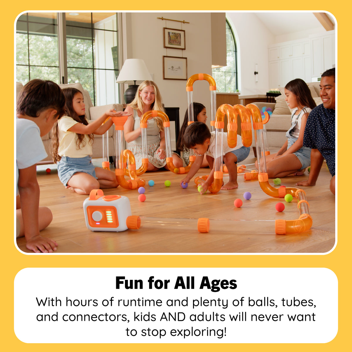 A group of children and an adult sitting on a wooden floor in a living room, playing with a large orange and clear marble-run style toy set with colorful balls. A text box at the bottom reads 'Fun for All Ages' and describes the toy's playful features.