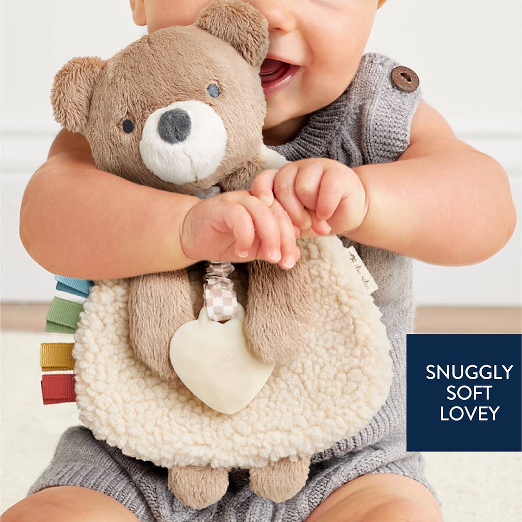 Baby holding a teddy bear toy on a white fluffy surface