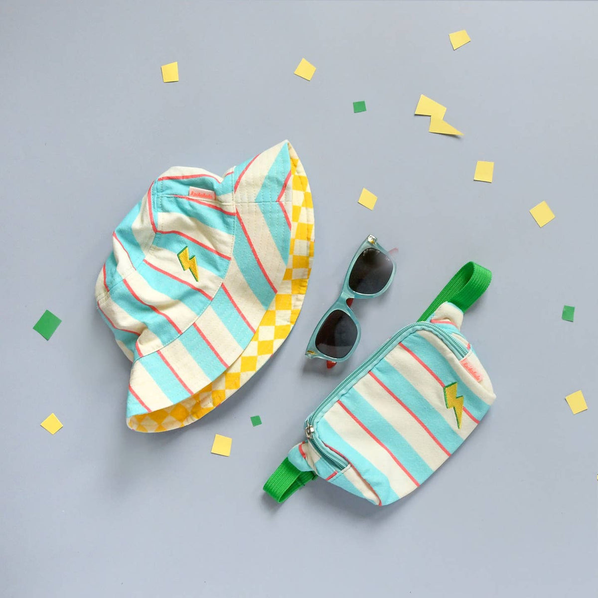 Colorful striped bucket hat and fanny pack with sunglasses on a light gray background