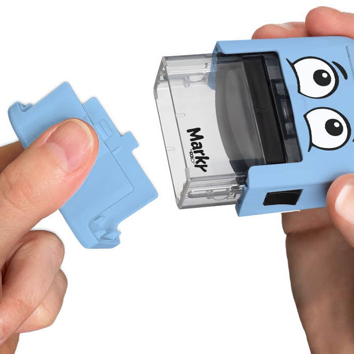 Blue Markr by OOLY stamp with cartoon face held by a hand on a white background