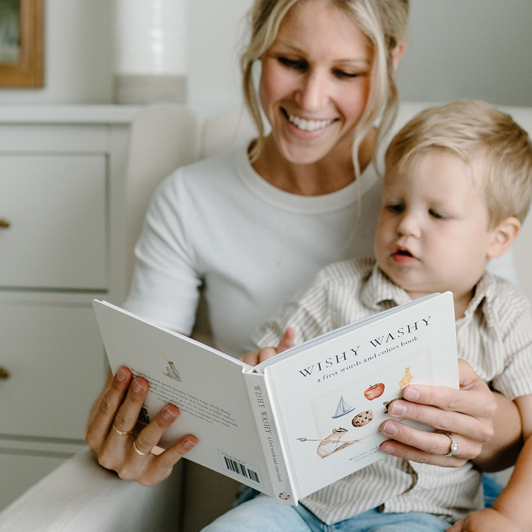 Woman reading a book to a child in a cozy room.