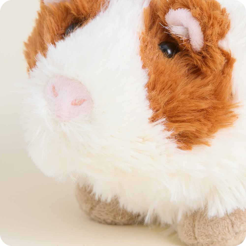 Close-up of a plush toy resembling a guinea pig with brown and white fur on a light background