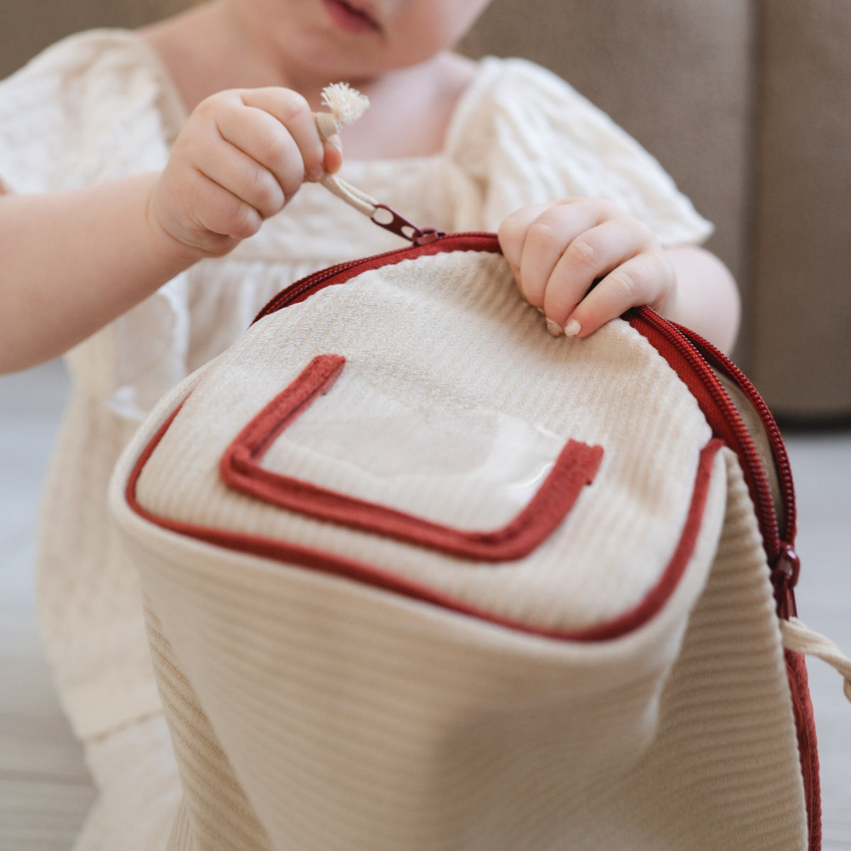Child holding a small white bag with red zipper