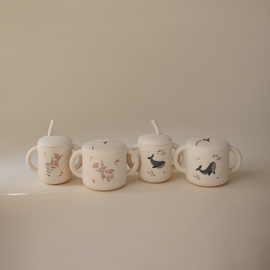 Four ceramic cups with animal illustrations on a beige background