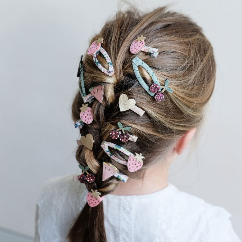 Girl with braided hair adorned with decorative hair clips on a plain background