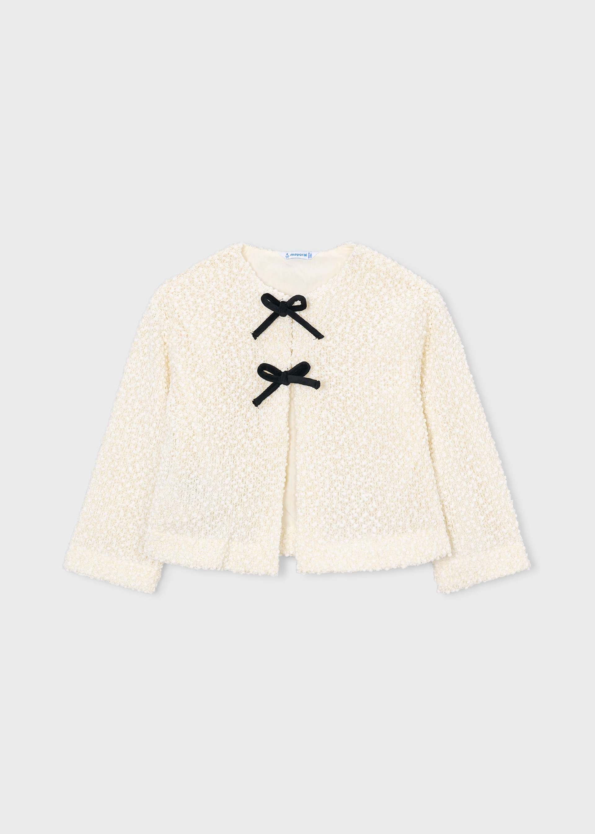 An off-white textured teddy fleece cardigan with three black bow details on the front, displayed flat against a light gray background.